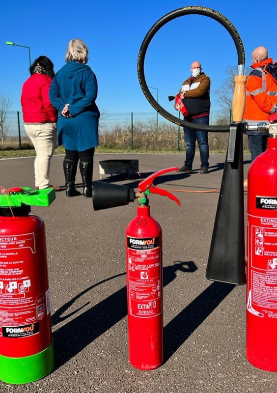 cours sur l'utilisation d'extincteur en extérieur, un formateur explique son fonctionnement au centre d'un cercle d’élèves