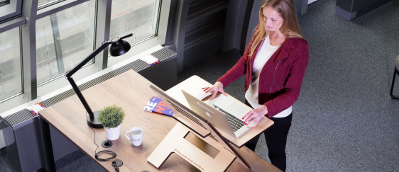 femme utilisant un bureau debout, ergonomique pour avoir une posture adaptée au travail